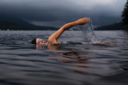 man swimming on body of water